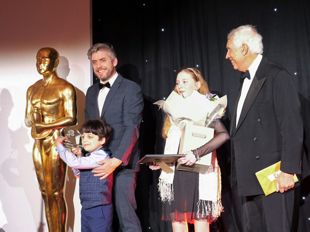 Two of our young winners with their guests celebrating winning an award on stage